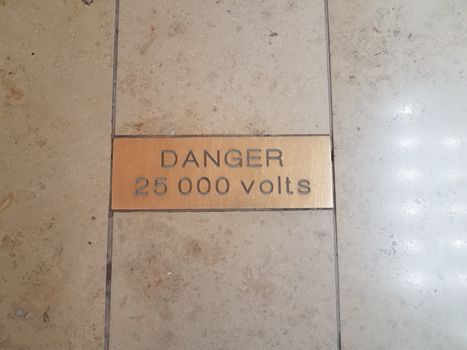 danger 25000 volts or voltage warning sign on tile floor