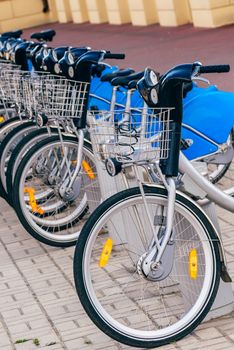 Parked Urban Silver Blue Bicycles on Rental Station.