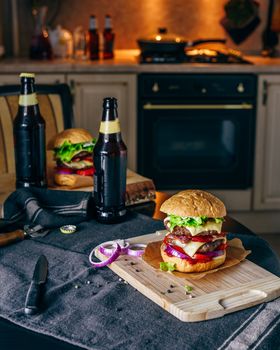 Dinner with Two Patties Cheeseburger and Couple Bottle of Beer on Kitchen Table.