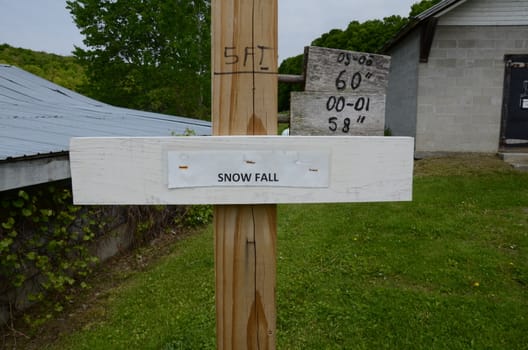 wood pole or stake with snowfall sign and snow depth markings in feet