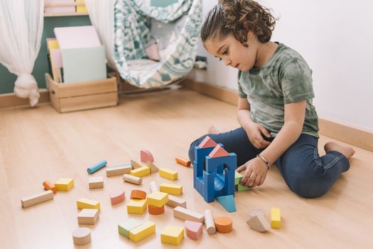 child little girl playing on the floor with wooden building block toys at home or kindergarten, educational toys for creative children
