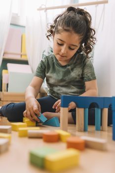 little girl playing in the floor with colorful wooden building block toys at home or kindergarten, educational toys for creative children