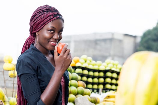 smiling young woman holding a tomato and tasted.