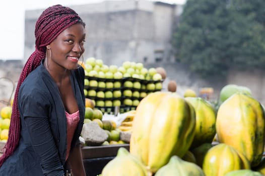 smiling young woman standing between shelves of fruit and looking at the camera.