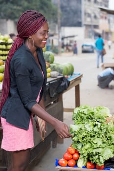 smiling young woman asks the price of a kilogram of vegetables.