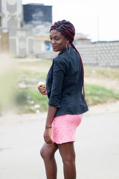 young woman holding an apple on the edge of the road.