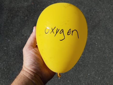 hand holding inflated yellow balloon with oxygen written on it