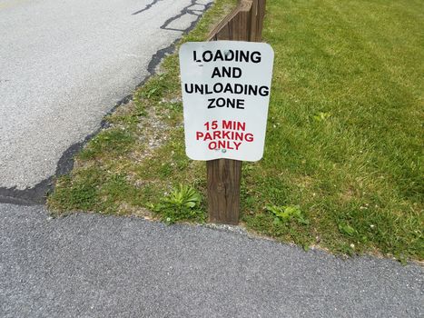 loading and unloading zone 15 minute parking only sign on wood stake