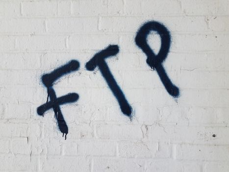 the letters ftp spray painted graffiti on white brick wall