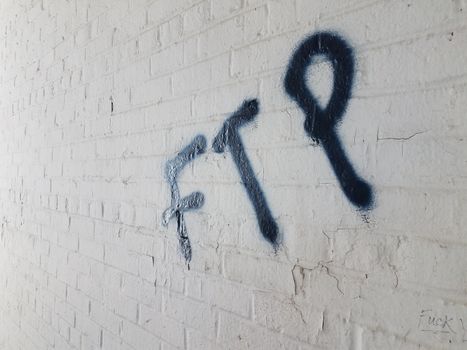 the letters ftp spray painted graffiti on white brick wall