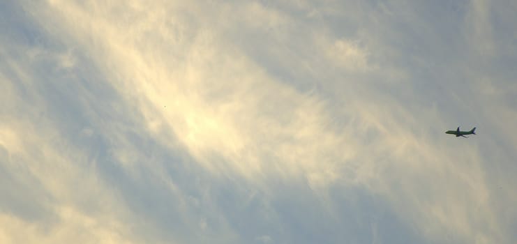 The silhouette of the aircraft in the sky against the background of cirrus clouds.