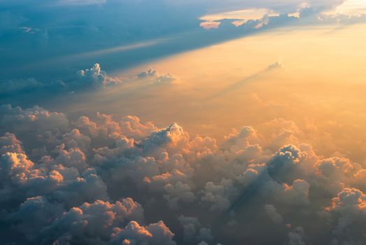 Beautiful aerial view of clouds at sunset, some clouds projecting dramatic shadows. View from airplane.