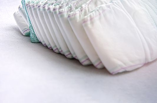 Group of disposable diapers arranged over a white changing table. Hygiene and health care for baby