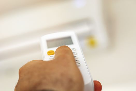 close-up view of a hand adjusting the air conditioning temperature using the remote control. Home comfort. Air conditioning and appliances