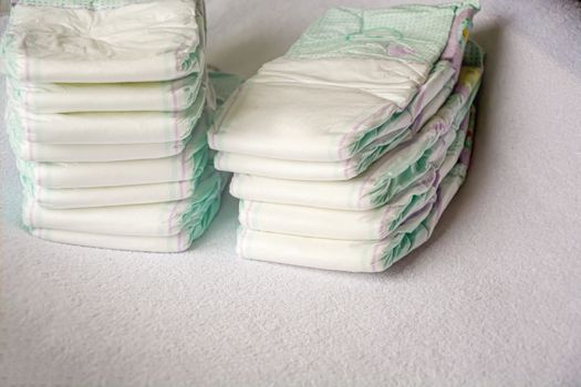 Group of disposable diapers arranged over a white changing table. Hygiene and health care for baby