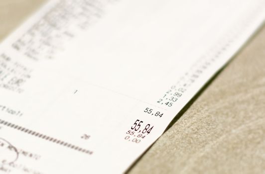 Close-up view of the total amount of supermarket grocery shopping printed on a paper receipt. Grocery shopping list