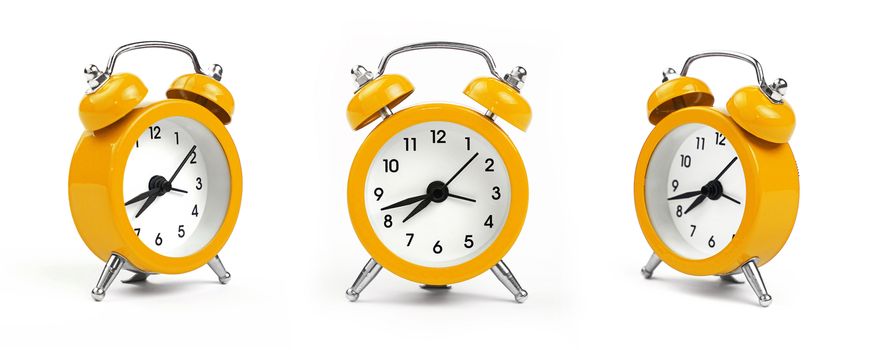 Three small yellow metal alarm clock with red bells over white background, close up, low angle view in different perspectives