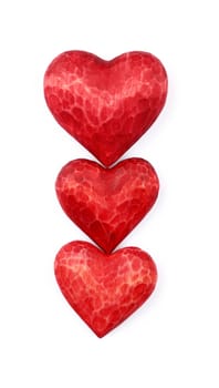 Close up three red painted natural wooden carved hearts isolated on white background