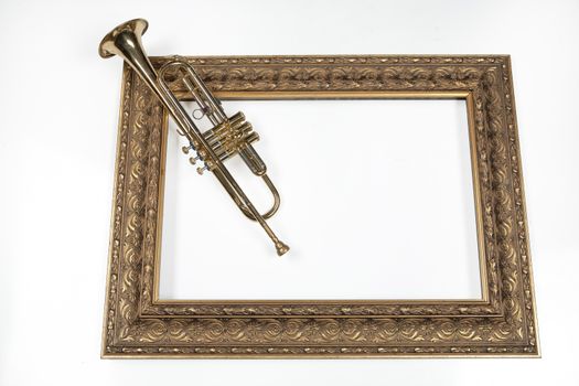 Trumpet and golden frame on an isolated studio background