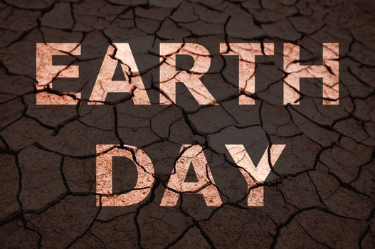 Earth Day text on dry cracked soil.