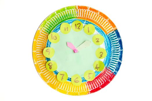 Colorful child handwork clock pointing at ten past two, isolated on white background