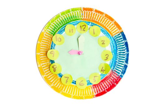 Colorful child handwork clock pointing at 9 o'clock, isolated on white background