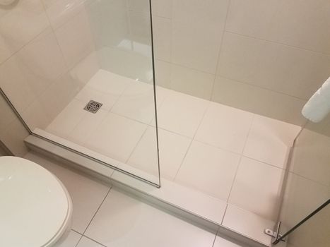 shower with white tiles and glass door and toilet in bathroom