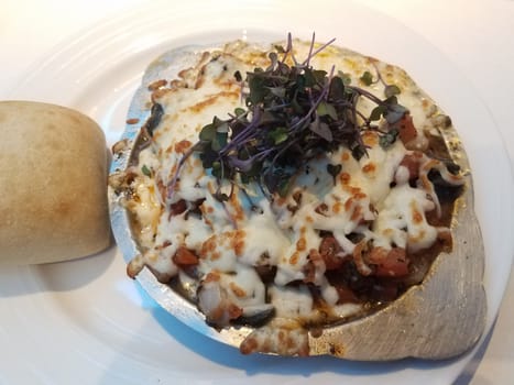 escargot or snails in metal plate with cheese and bread and sprouts