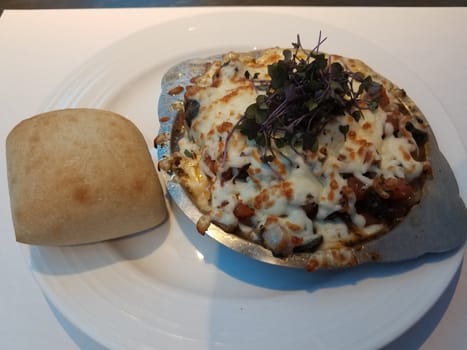 escargot or snails in metal plate with cheese and bread and sprouts