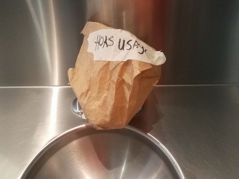 metal sink in bathroom with out of order sign in French and brown paper bag