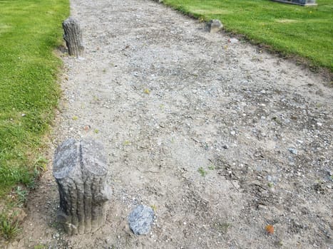 tree stump cement grave markers in cemetery with path or trail