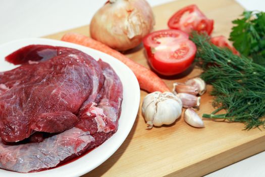 Portion of raw beef meat for cooking near vegetables