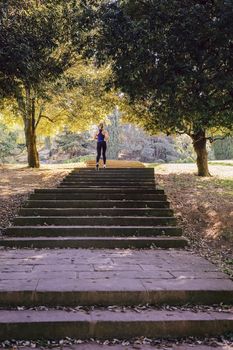 back view of young sports woman running upstairs during fitness workout at the park in morning with sunlight, sport and healthy lifestyle concept, vertical photo