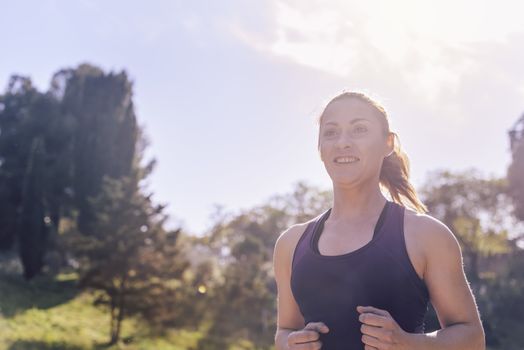 portrait of young sports woman running during outdoor workout at the park at the morning with sunlight, sport and healthy lifestyle concept