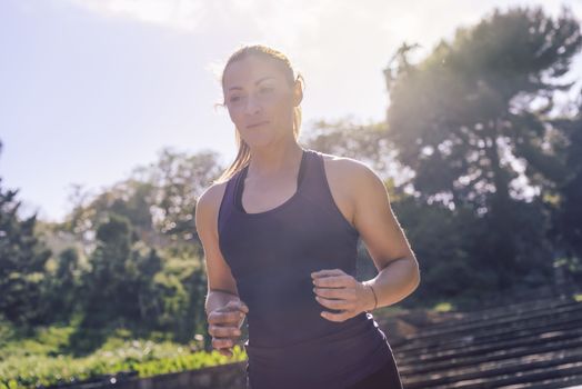 young sports woman running during outdoor workout at the park at the morning with sunlight, sport and healthy lifestyle concept