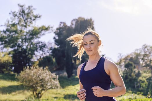 portrait of happy beautiful sports woman running during outdoor workout at the park at the morning with sunlight, sport and healthy lifestyle concept