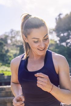 vertical portrait of happy sports woman running during outdoor workout at the park at the morning with sunlight, sport and healthy lifestyle concept