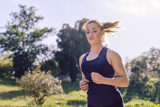 happy beautiful sports woman running during outdoor workout at the park at the morning with sunlight, sport and healthy lifestyle concept