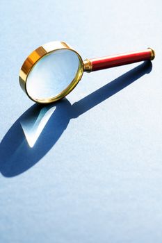 Nice retro magnifying glass under sunlight on gray background
