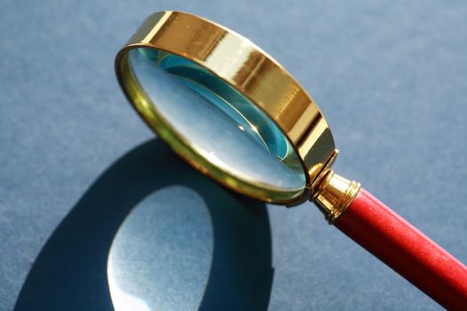 Nice retro magnifying glass under sunlight on gray background