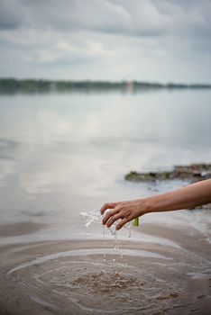 hand pick up plastic bottle from water. save environment and beat plastic pollution , Selective focus