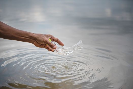 hand pick up plastic bottle from water. save environment and beat plastic pollution , Selective focus