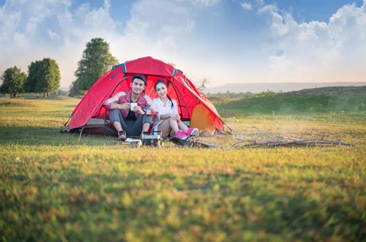 Couple of travelers spending time in tent near campfire