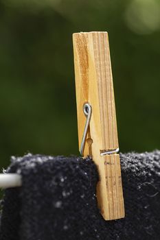close up of a wood clothesline pin hold a black shirt on a line