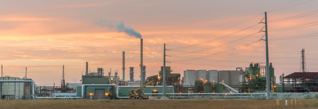 Panorama view typical oil refinery with smoke stacks gas flare at sunrise in Corpus Christi, Texas, America. Oil or gas production sites background