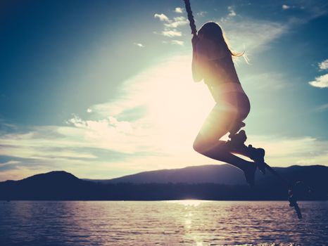 Retro Style Summertime Image Of A Girl Swinging Into A Lake At Sunset With Copy Space