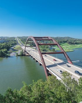 Elevated view of Pennybacker Bridge or 360 Bridge with car traffic at daytime. A landmark in Austin, Texas, USA. Top of Town Lake, Colorado River and Hill Country green landscape
