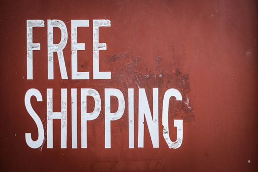 Grungy Free Shipping Sign On The Side Of A Red Metal Shipping Container