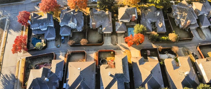 Panorama straight looking aerial view of typical houses colorful fall color near Dallas, Texas. Fly-over single-family home with large garden, swimming pool. Light snow on roof in cold early morning