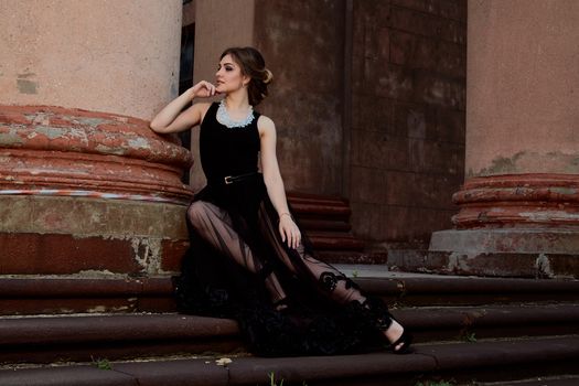 Young attractive woman in the sexy see-through, transparent, transpicuous, diaphanous, clear black dress near the ancient building. Vintage building. Fashion woman. Young woman modern portrait.